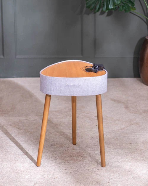 Small round stool with wooden legs and a light gray cushioned seat against a neutral background.