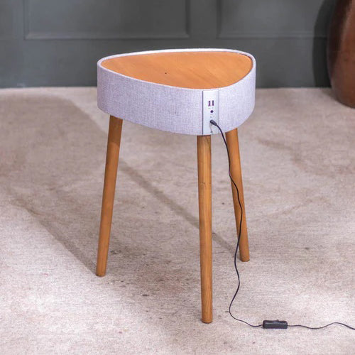 Small round table with wooden legs and a gray top on a carpeted floor.