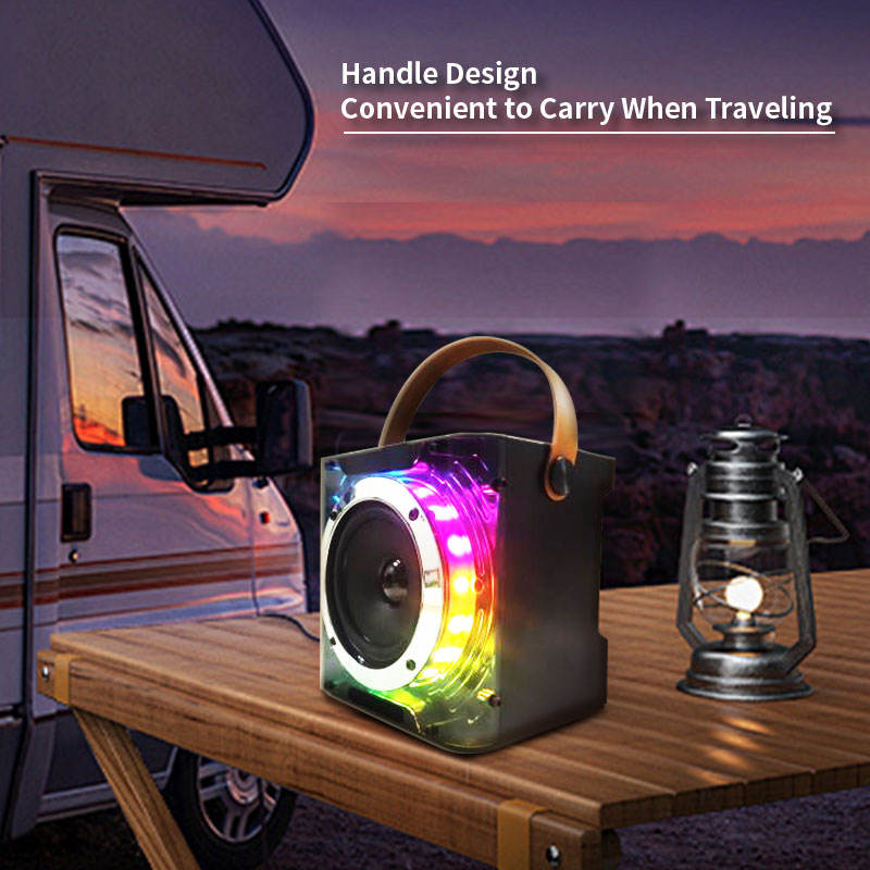 Portable speaker with colorful lighting on a table next to a camper van at sunset.