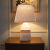 Decorative table lamp with a textured base and lampshade on a wooden surface.