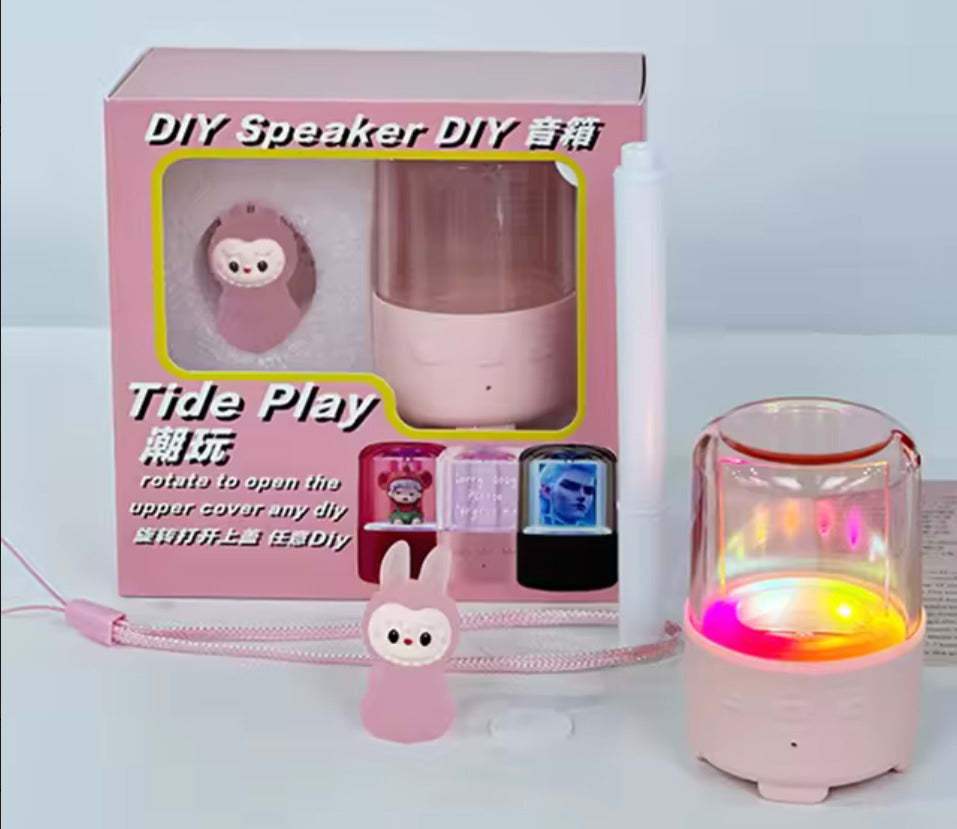 Pink DIY speaker with packaging and small monkey figurine on a light blue background
